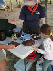 Frosting a freshly baked solar oven chocolate cake.